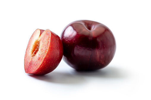 One Red plum, and one sliced plum on white background