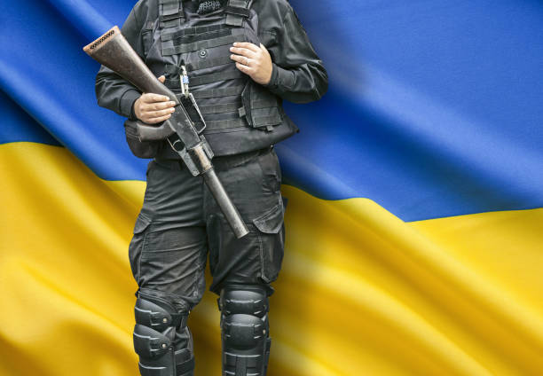 Army soldier with weapon standing in front of ukrainian flag stock photo