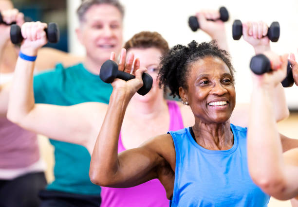 Senior African-American woman in exercise class Close-up of a senior African-American woman in her 60s enjoying an exercise class. She is with a multiracial group of mature adults sitting on fitness balls and lifting hand weights. exercise class stock pictures, royalty-free photos & images