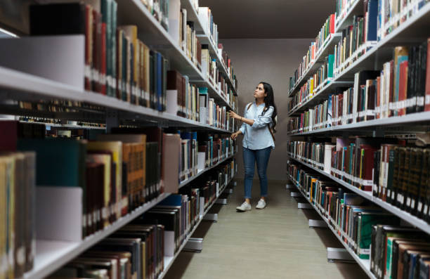 istock Female student searching book in library 1372784279