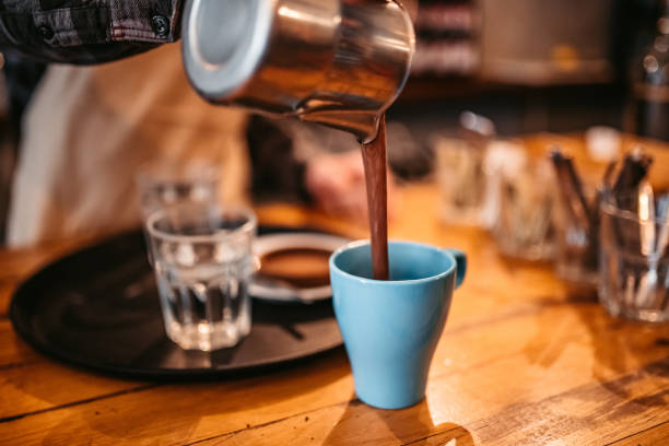 Barista pouring coffee in cup on bar counter, close up.