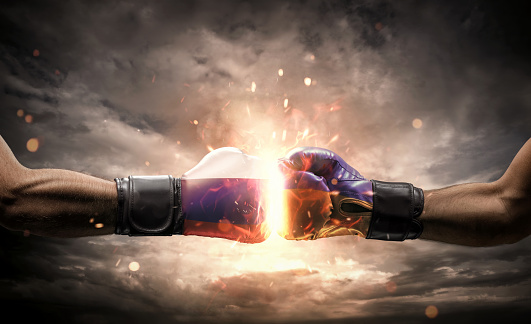 Conflict, war concept. Close up of two fists hitting each other over dramatic sky