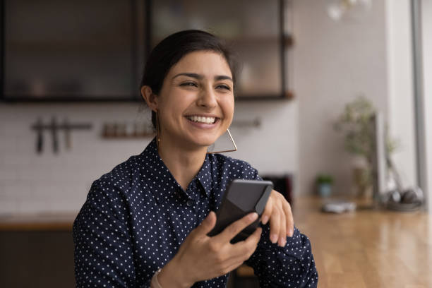 istock Indian woman sit indoor holding smartphone laughing 1372785521