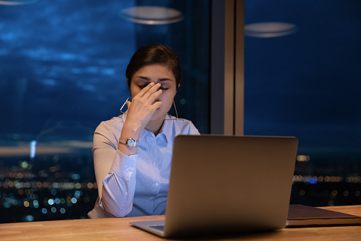 Tired Indian office employee work late with laptop in office