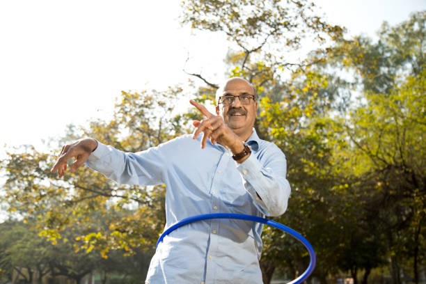 istock Senior man exercising with hula hoop at park 1372787324