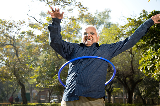 Senior man exercising with hula hoop at park