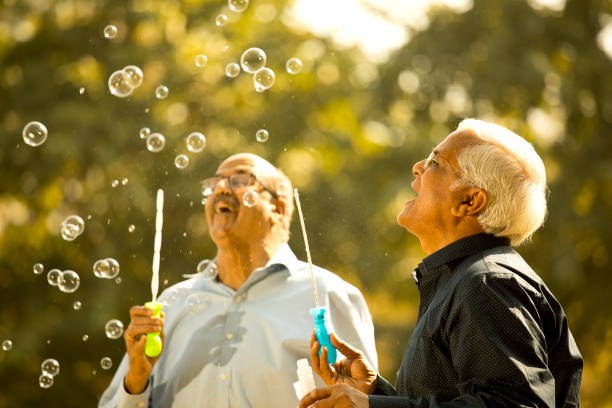 istock Senior men enjoying blowing bubbles at park 1372788775