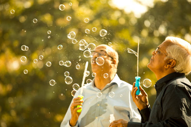 istock Senior men enjoying blowing bubbles at park 1372788835