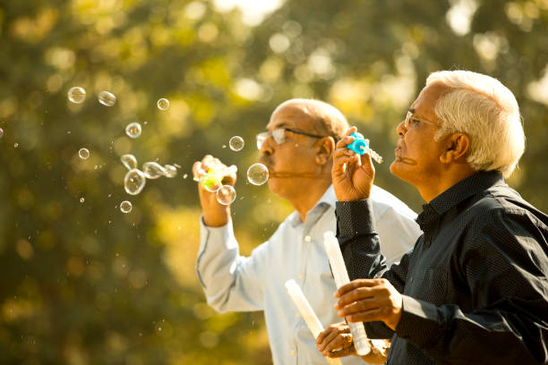 istock Senior men enjoying blowing bubbles at park 1372788918
