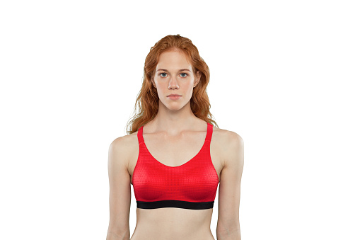 Female athlete poses on a white background. Studio portrait of woman wearing red sporty tank top. Woman in a calm pose