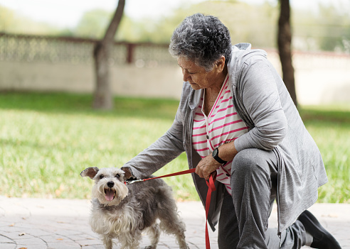 Happy senior woman enjoying walk and petting dog