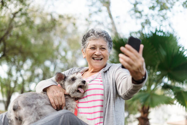 Cheerful senior woman with dog taking a selfie stock photo