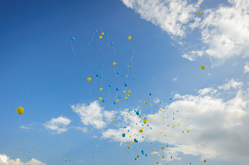 Balloons in color of Ukraine flag yellow and blue colors on a cloudy sky background. No war