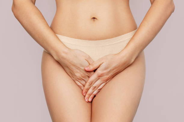 young woman in underwear holding her crotch with hands, suffering from cystitis on beige background - klamydiatest bildbanksfoton och bilder