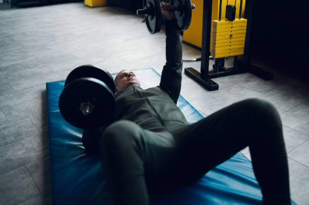istock Man lying on the mat in the gym and training with dumbbell 1372801236