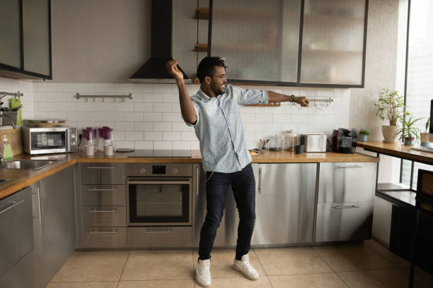 Happy handsome young African American man dancing in kitchen.