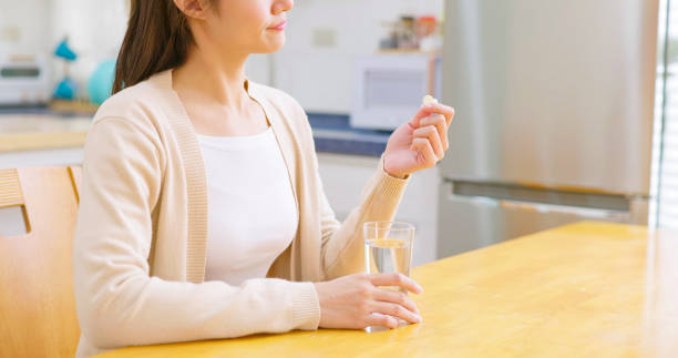 女性はビタミンや薬を飲む - 喉の痛み 日本人 ストックフォトと画像