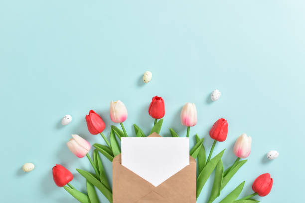 istock A bouquet of tulips with a postcard and Easter eggs on a blue background. 1372805067