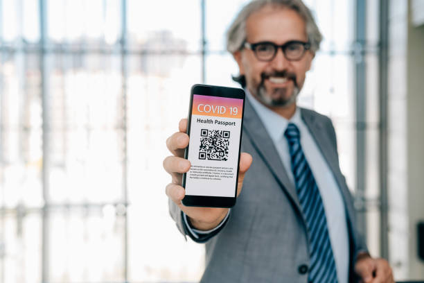 istock Unrecognizable Businessman Showing Digital Health Passport App on a Mobile Phone Screen While Standing In Front Of Big Window 1372809095