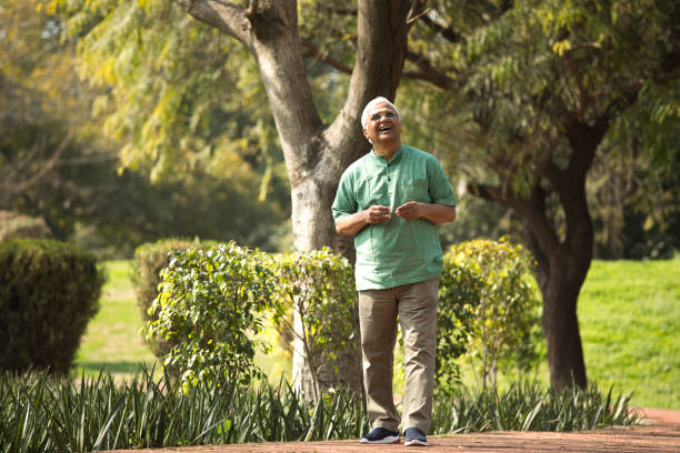 Thoughtful senior man walking at park Thoughtful senior man walking at park indian man walking in park stock pictures, royalty-free photos & images