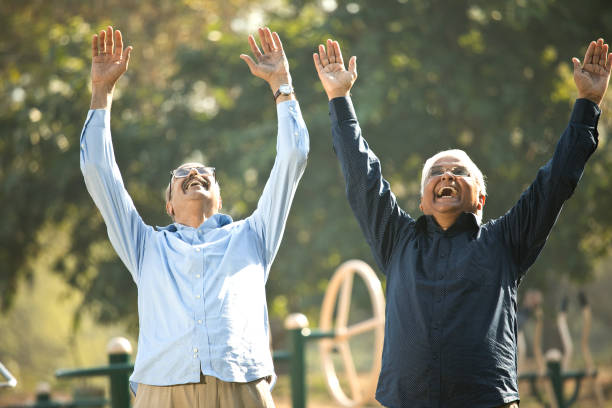 istock Two senior men laughing with arms raised at park 1372810970