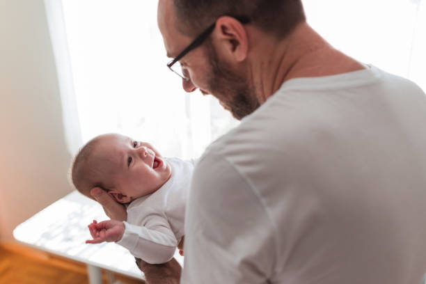 Man holding an adorable young smiling baby in his arms
