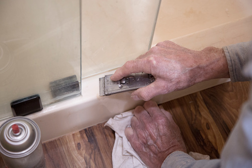 Plumber or homeowner DIY repairing leaking shower door.