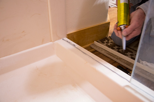 Plumber or homeowner DIY repairing leaking shower door.
