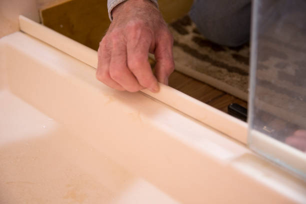 Plumber or homeowner DIY repairing leaking shower door. stock photo