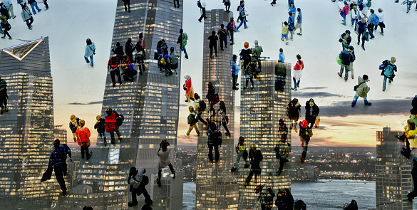 Shot of unrecognizable people climbing on skyscrapers superimposed over an illuminated cityscape. The city is NYC, Hudson Yards.