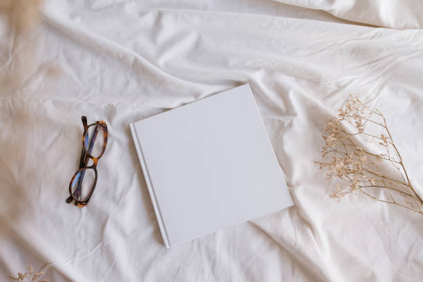 istock White book mockup with some glasses and dry sheets on the bed. 1372822174