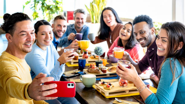 friends taking selfie on breakfast time drinking juices and eating cakes - people having fun at fashion cafeteria - life style concept with happy men and women at cafe bar - selective focus on sides - breakfast eating people teens imagens e fotografias de stock