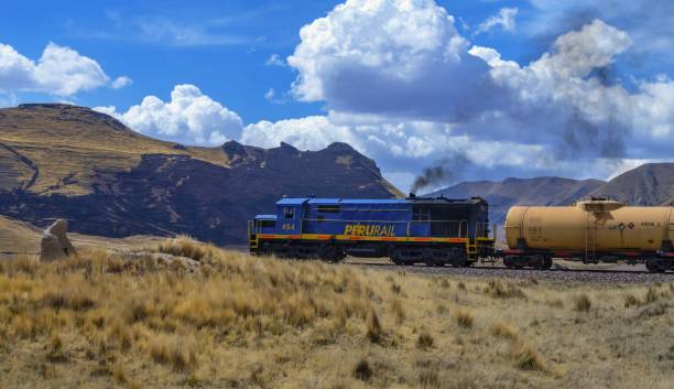 Tirapata, Peru, November 16, 2021: A freight train of Peruvian Railways runs along the Andes ridge on a sunny day.