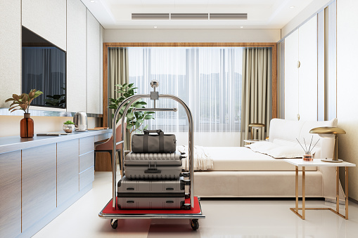 Lujosa habitación de hotel con carrito de equipaje, cama doble, mesas de noche, televisor y vistas al mar desde la ventana photo