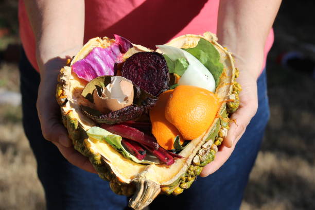 istock Woman holding compostable food scraps in hearth-shaped half pumpkin 1372828600