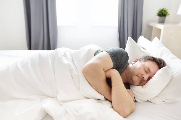 Mature man is sleeping in bed at home early in the morning. stock photo