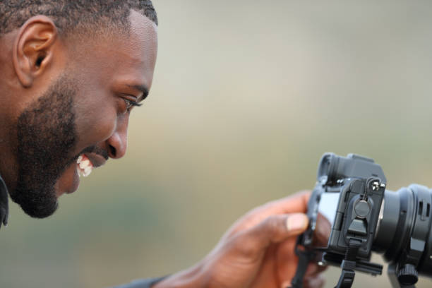 istock Photographer with black skin checking mirrorless camera 1372831945