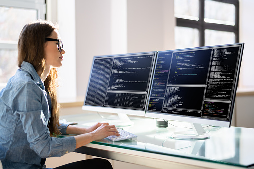 Programmer Woman Coding On Multiple Computer Screens