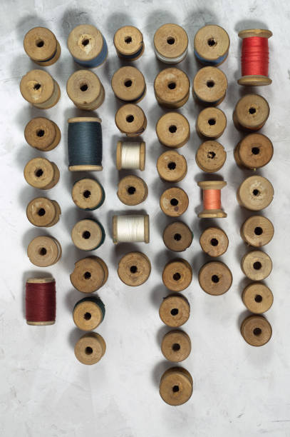 Pattern of coils of antique thread The threads on the wooden bobbin are arranged in a pattern on a gray background. Vintage sewing threads for needlework.Top view, flat lay. wooden spool stock pictures, royalty-free photos & images