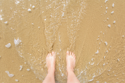 woman's feet getting wet from a wave on the beach
