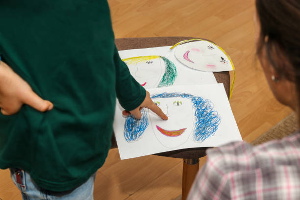istock A Boy Pointing Finger And Showing His Drawing To Teacher. 1372845897