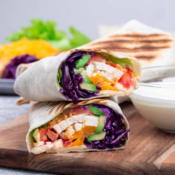 istock Chicken wraps with red cabbage, avocado, tomato, lettuce and cheddar cheese, on wooden board, square 1372845902