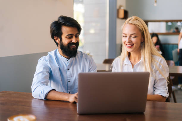 istock Close-up front view of two multiracial smiling creative workers discussing project during meeting in cafe. 1372846695