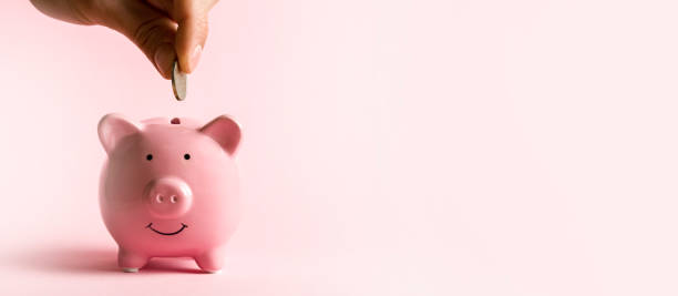 istock Hand puts a coin in a piggy bank. 1372852580