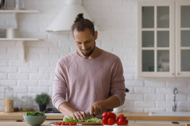 istock Smiling handsome young man cooking alone in kitchen. 1372859428