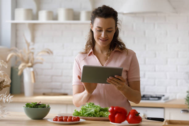 istock Happy young woman using digital computer tablet, cooking at home. 1372859429