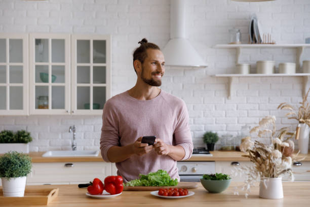 istock Distracted from cooking food happy young man using smartphone. 1372859434