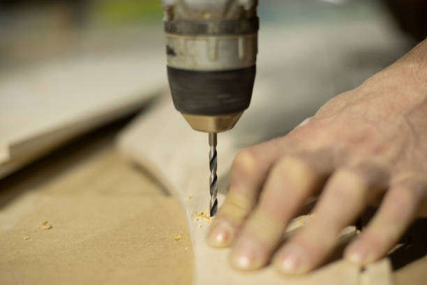 Drill bit in wood. Drilling hole in board. Guy works with tool. stock photo