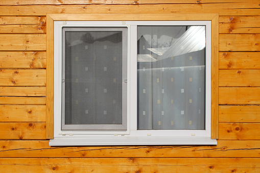 A double-glazed window in a wooden house made of timber. Close-up. Background. Texture.