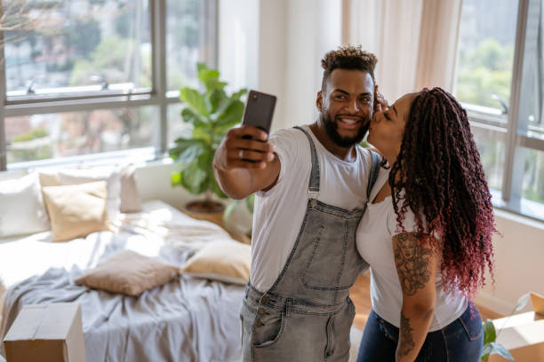 istock Young couple taking selfies surrounded by moving boxes 1372863561